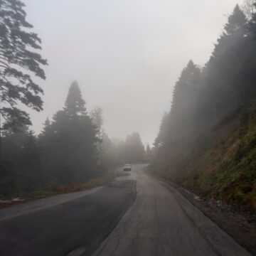 Urban Legends: 9 Tales Where Familiar Places Turn Dark A car on a foggy road winding through forested mountains on Evia, Greece.