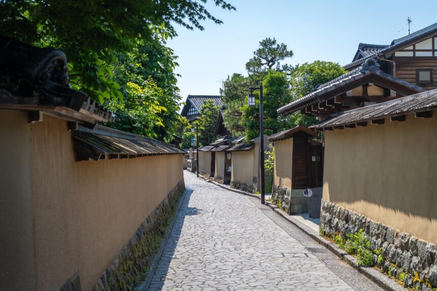 An empty stone-paved street lined with plaster walls and tiled roofs in Nagamachi, Kanazawa, Japan.