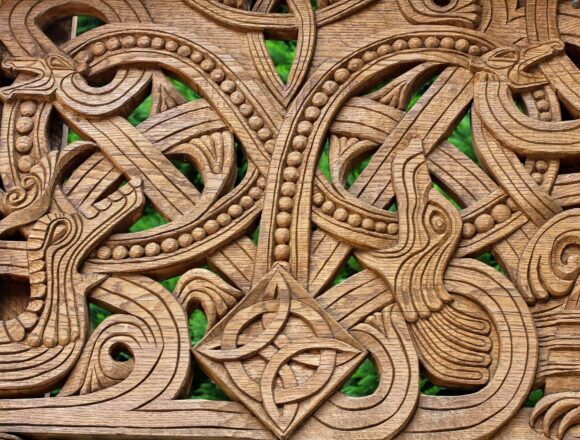 Norse Mythology Creatures: Kin and Killers of the Gods Intricate wooden carving with intertwined animal forms, looping serpents and a central knot.